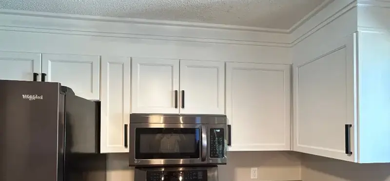 Stacked crown molding running along the top of white upper cabinets
