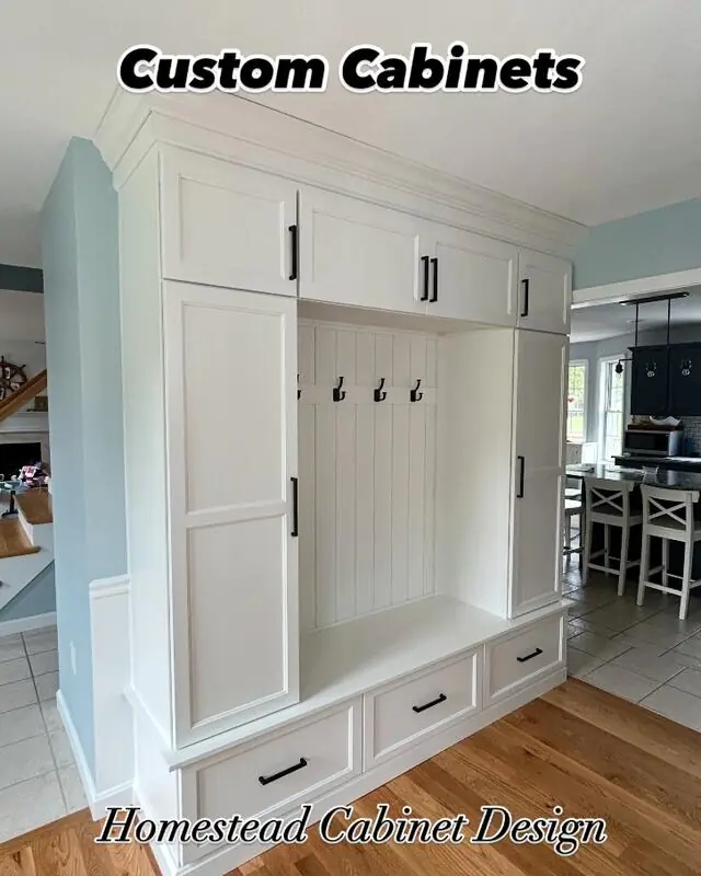 White custom mudroom cabinets with hooks and a bench