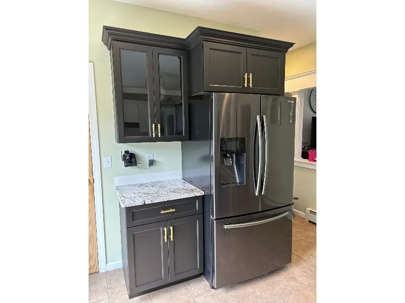 Custom built-in cabinet in dark charcoal finish with glass-door uppers, brass hardware, and granite countertop