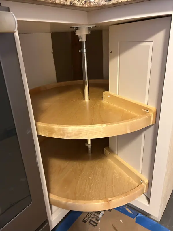 Door-mounted wood lazy susan rotated open in a white corner cabinet