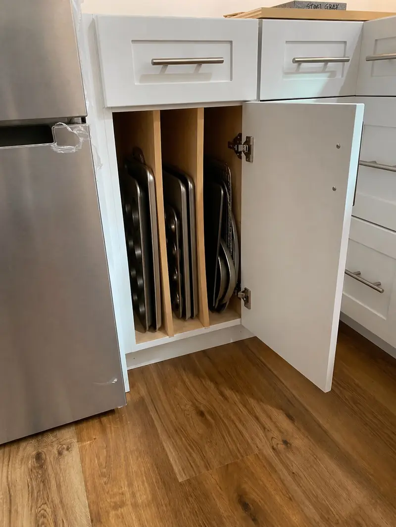 Base cabinet with vertical dividers holding sheet pans and trays