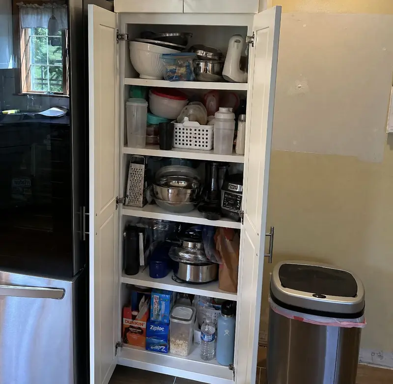 Crowded fixed shelves in a tall pantry cabinet before adding pull-outs